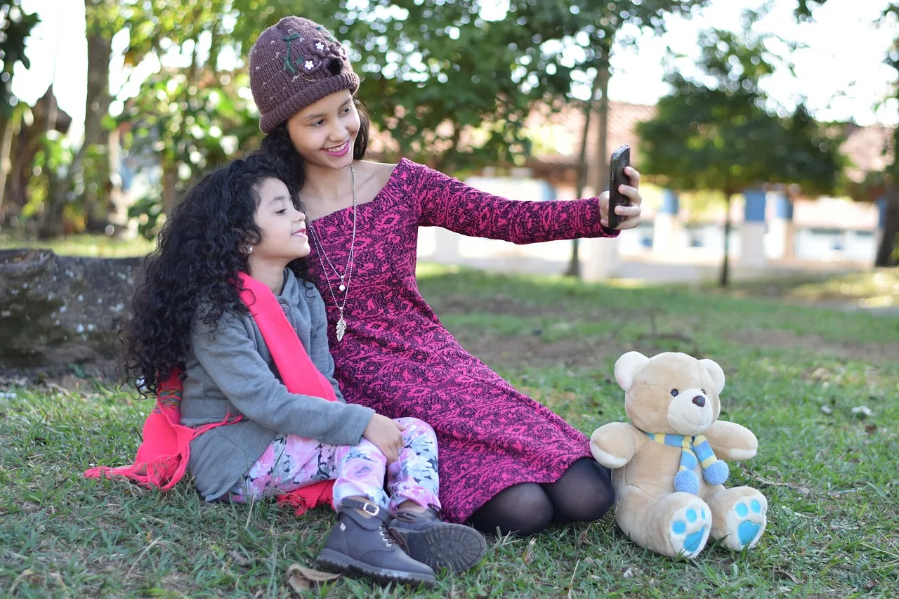 family, selfie, park, taking photo, woman, girl, child, kid, teddy bear, lawn, camera, smartphone, cell phone, outdoors